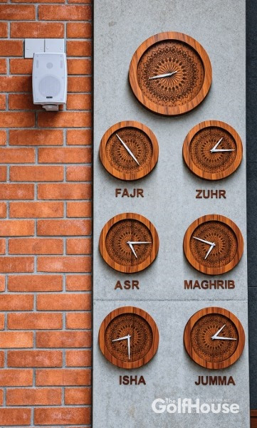 At Kurmitola Golf Club's new mosque Inside, the prayer clocks bring another rhythm into view. Their patterned wooden faces sit against the brick and concrete, marking the times of the daily prayers and Jumma. 